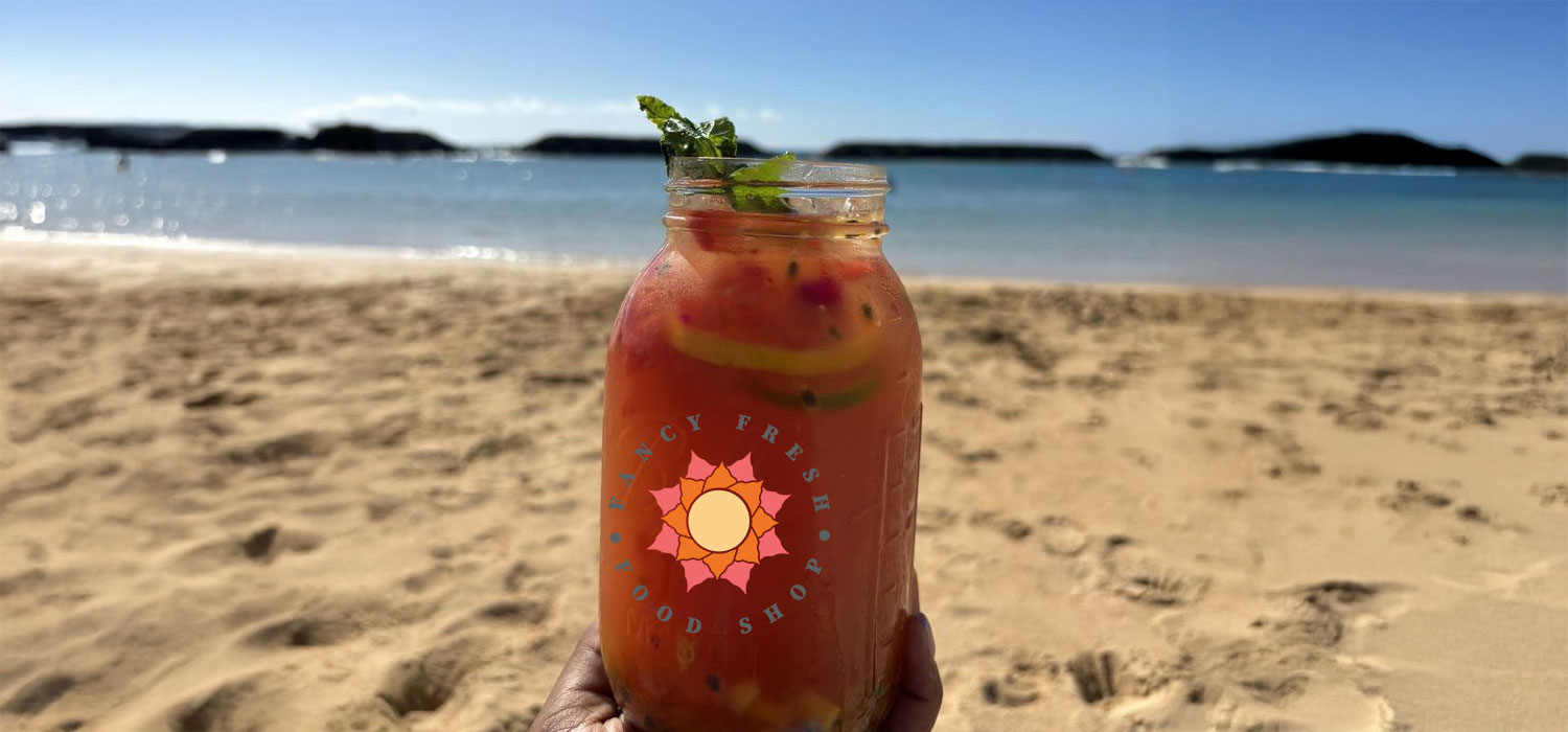 Fancy Fresh Juice Shop logo on a jar of juice at the beach